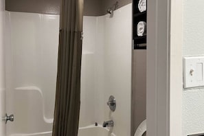 A bathroom with a bathtub, a shower, a toilet, and a towel rack.