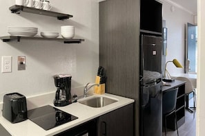 A compact kitchenette with a coffee maker, toaster, and sink.