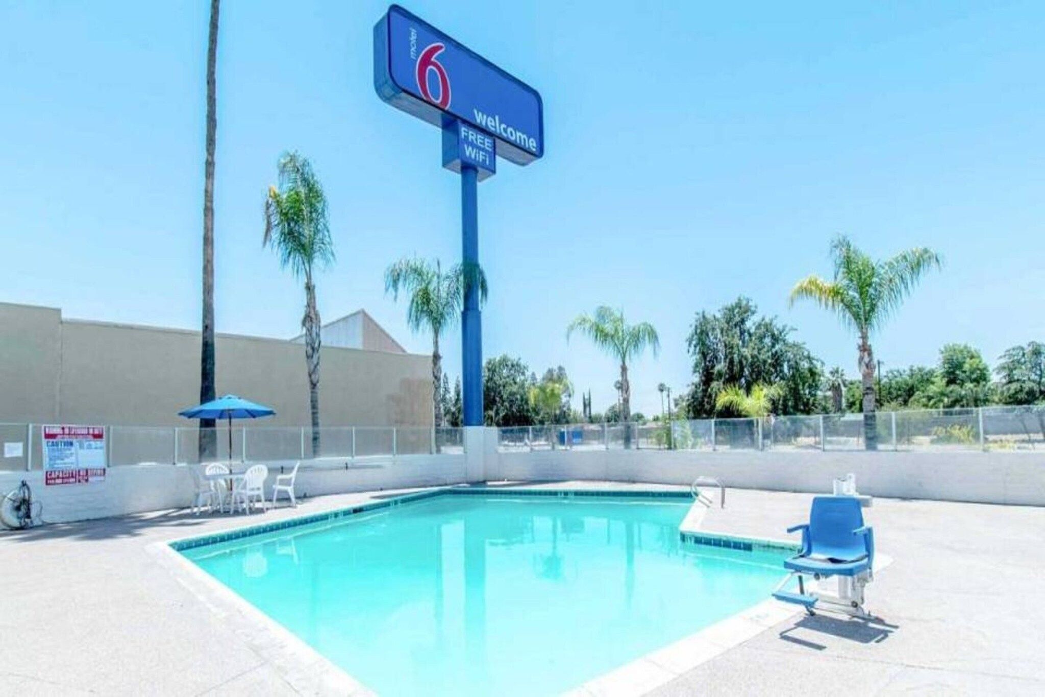Piscina azul cristalina con sillas de descanso y un cartel que indica wifi gratuito.