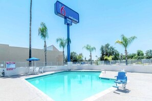 Piscina azul cristalina con sillas de descanso y un cartel que indica wifi gratuito.