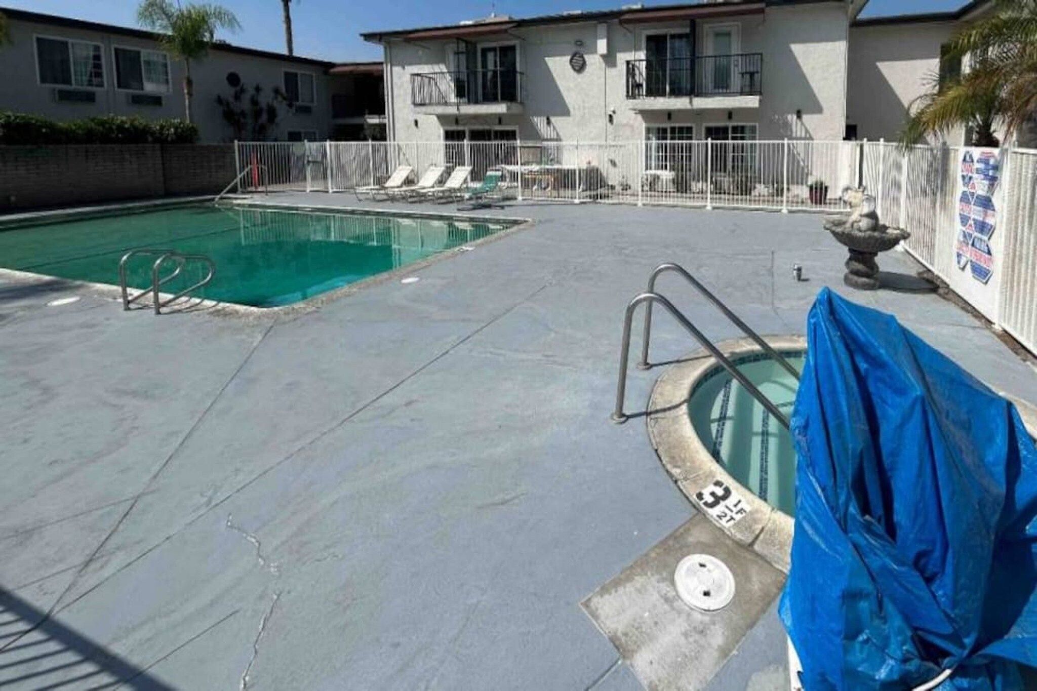 Ein Schwimmbeckenbereich mit Sprungbrett, einem überdachten Whirlpool und einem umzäunten Poolbereich.