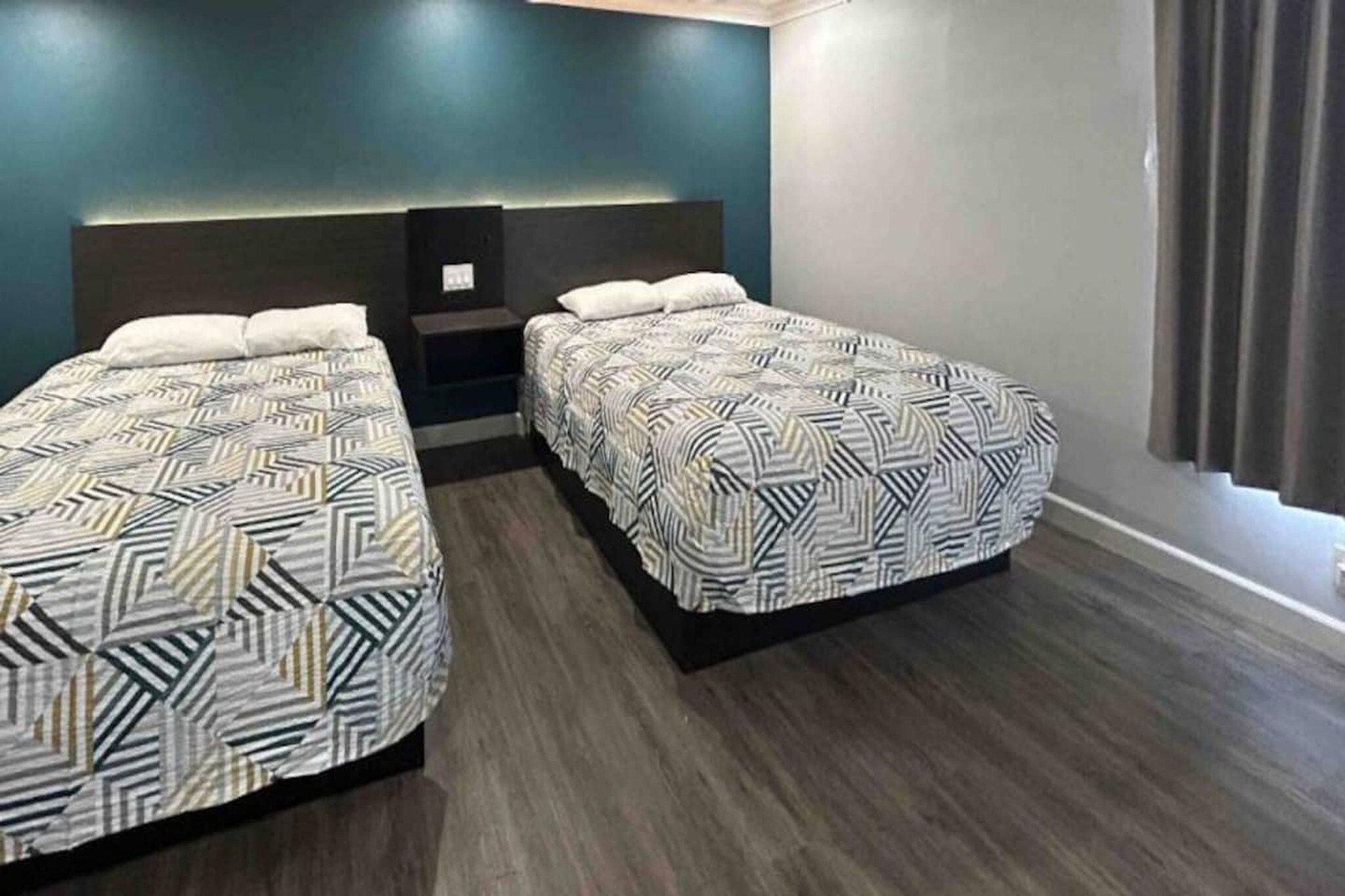Ein Hotelzimmer mit zwei Betten, einem dunklen Holzboden und einem modernen Design.