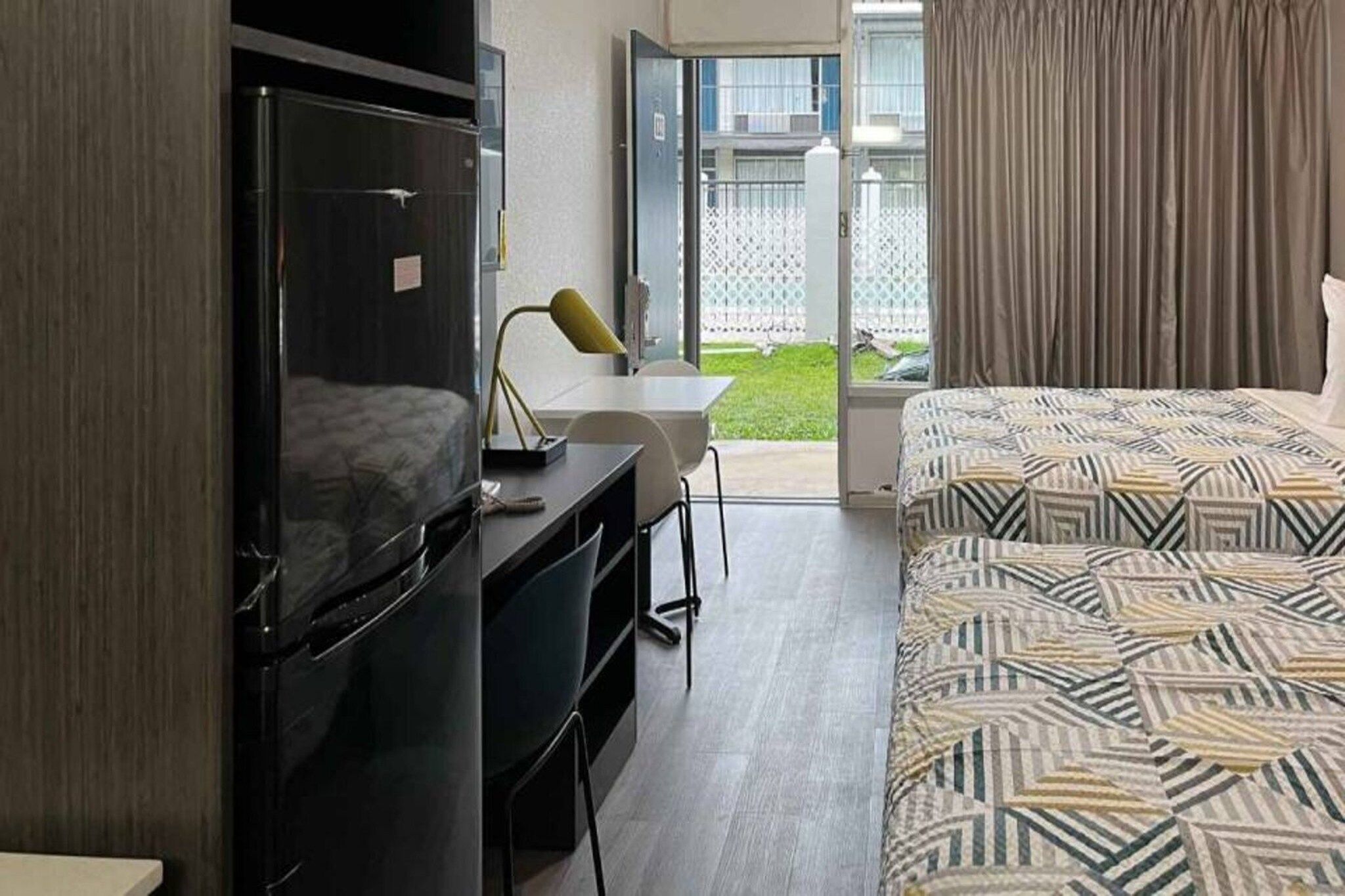 Quarto de hotel com uma cama, escrivaninha, televisão e vista para o exterior.