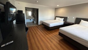 Hotellihuone, jossa on kaksi sänkyä, työpöytä, televisio ja kylpyhuone.