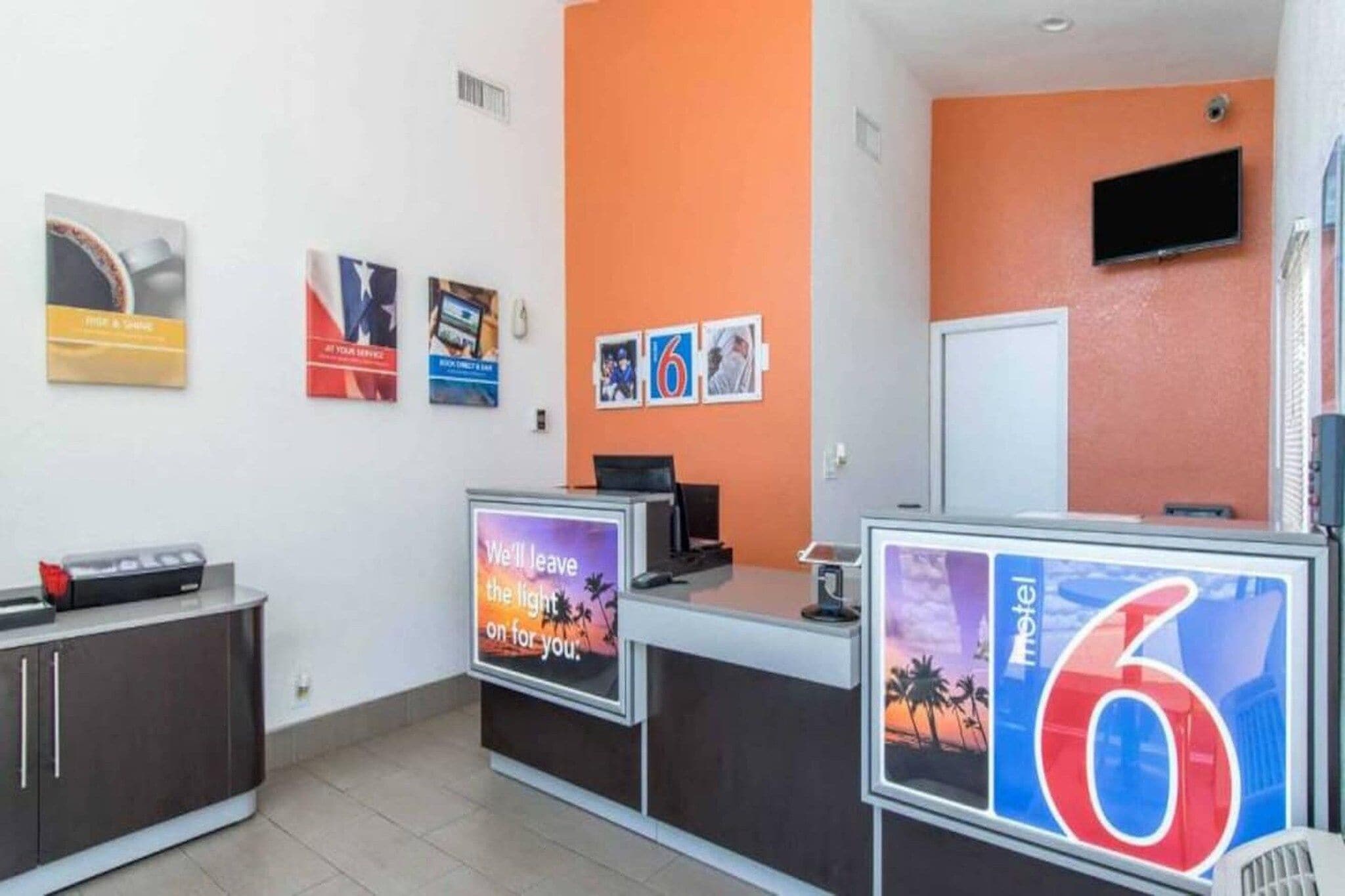 Un área de recepción con mostrador, un televisor y un cartel que indica el número 6.