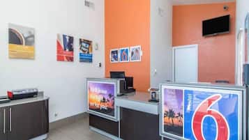 Un área de recepción con mostrador, un televisor y un cartel que indica el número 6.