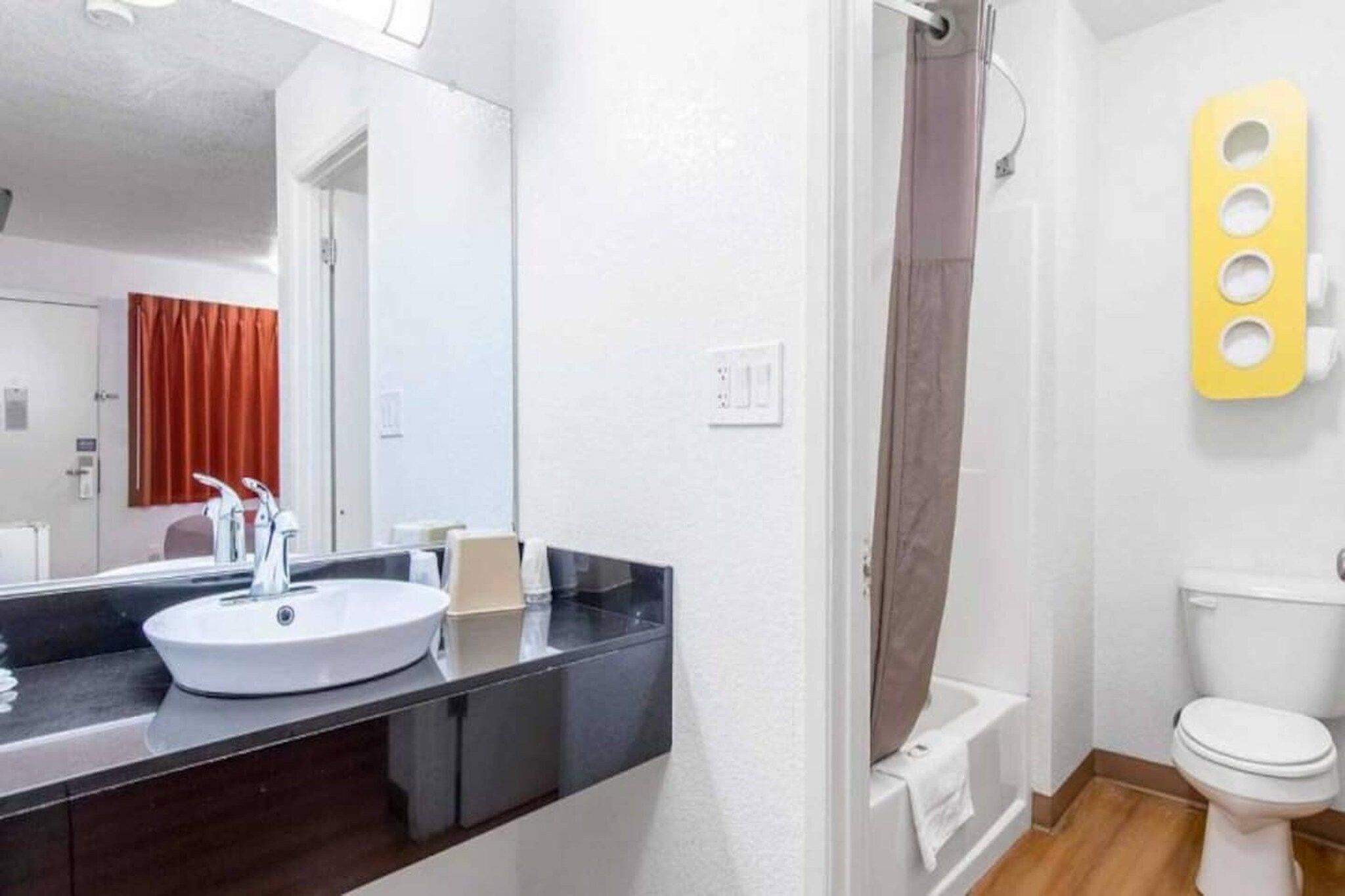 Een badkamer met een wit wastafel, een spiegel, een toilet en een douchehoek.
