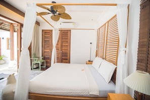 Une chambre à coucher avec un lit à baldaquin, des volets en bois et un ventilateur de plafond.