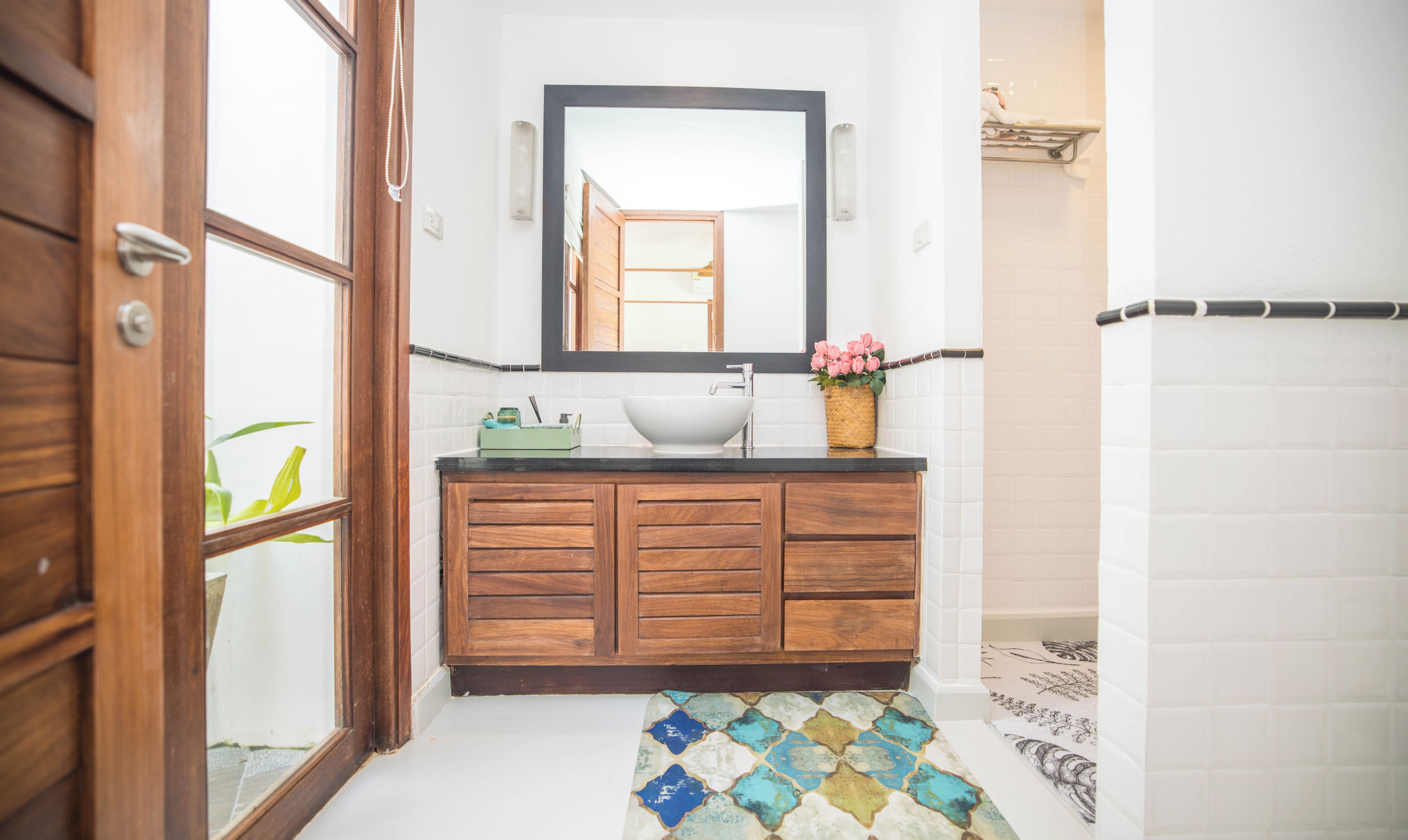 Un baño con tocador de madera, un lavamanos blanco y un espejo encima.