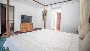 Un dormitorio con una cama grande, un aparador de madera, un televisor y un cuadro en la pared.