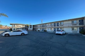Un motel con edificios de dos pisos, un estacionamiento y dos coches blancos estacionados.