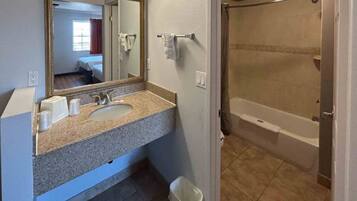 A bathroom with a sink, mirror, and shower.