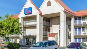 A hotel with a prominent '6' sign, multiple balconies, and a parking lot with cars. - 2 Queen Beds | Non-Smoking, Kitchen (Fresno CA)