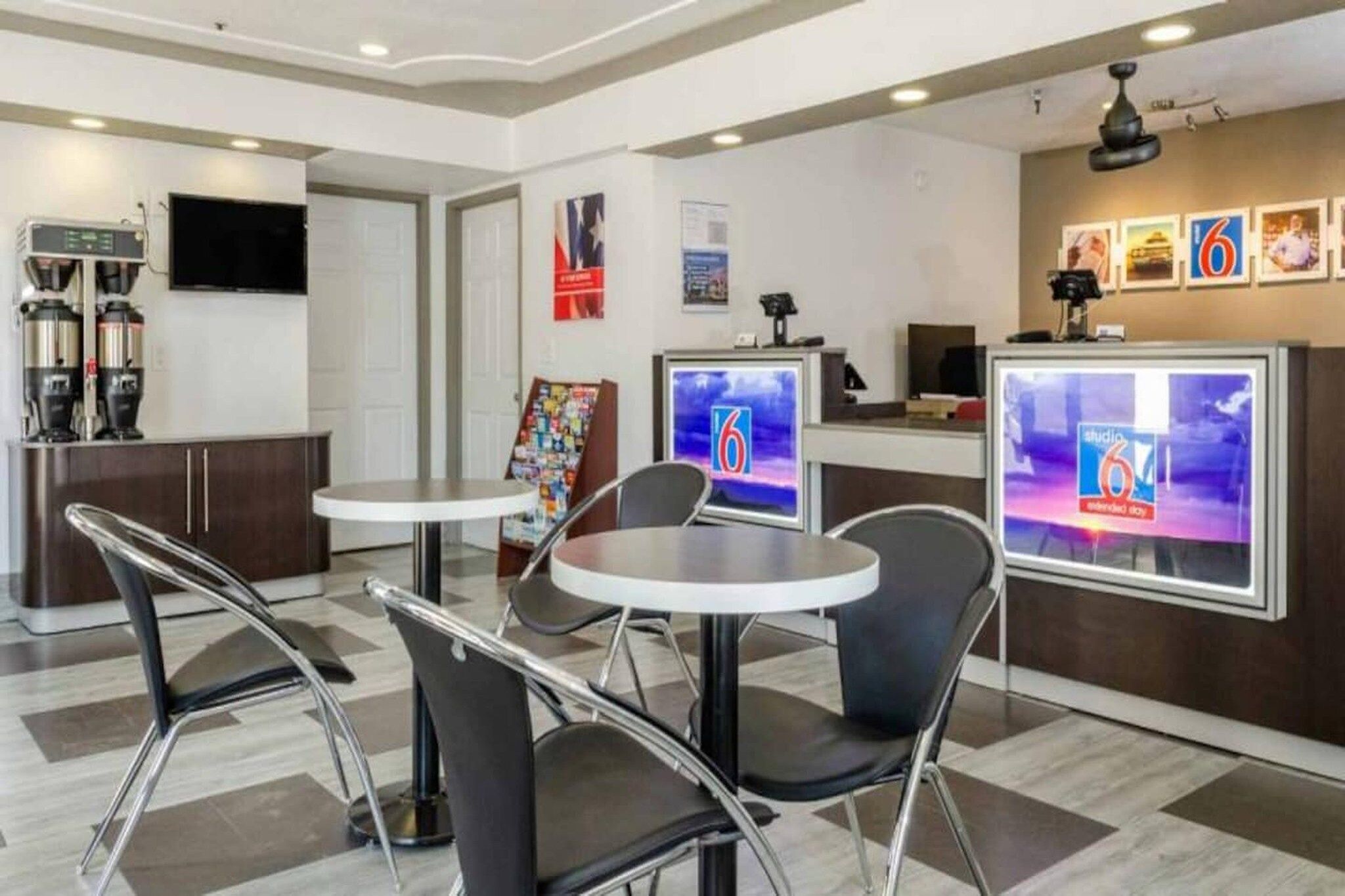 A modern hotel lobby with a reception desk, seating area, and a coffee machine.