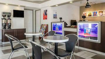 A modern hotel lobby with a reception desk, seating area, and a coffee machine.
