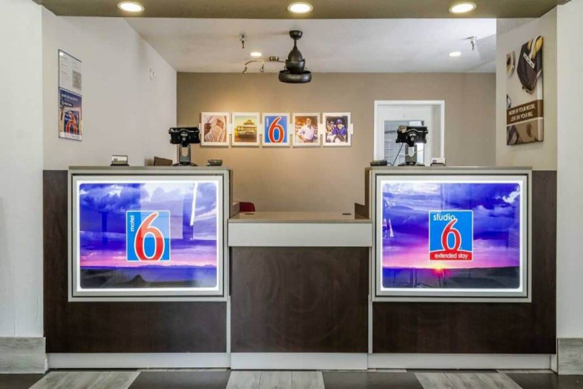 A reception desk with two monitors displaying the number 6 and the text 'studio 6 extended stay'.