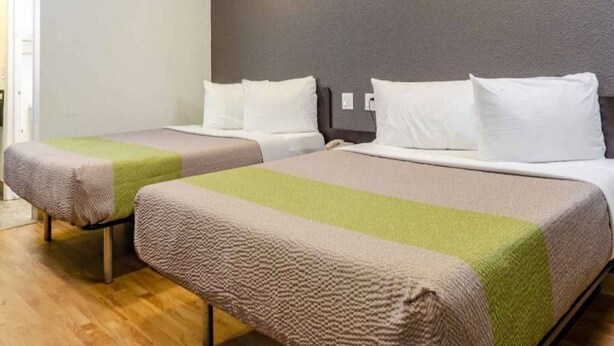 Two twin beds with a neutral color scheme, a wooden floor, and a plain wall. - 2 Queen Beds | Non-Smoking, Kitchen (Fresno CA)