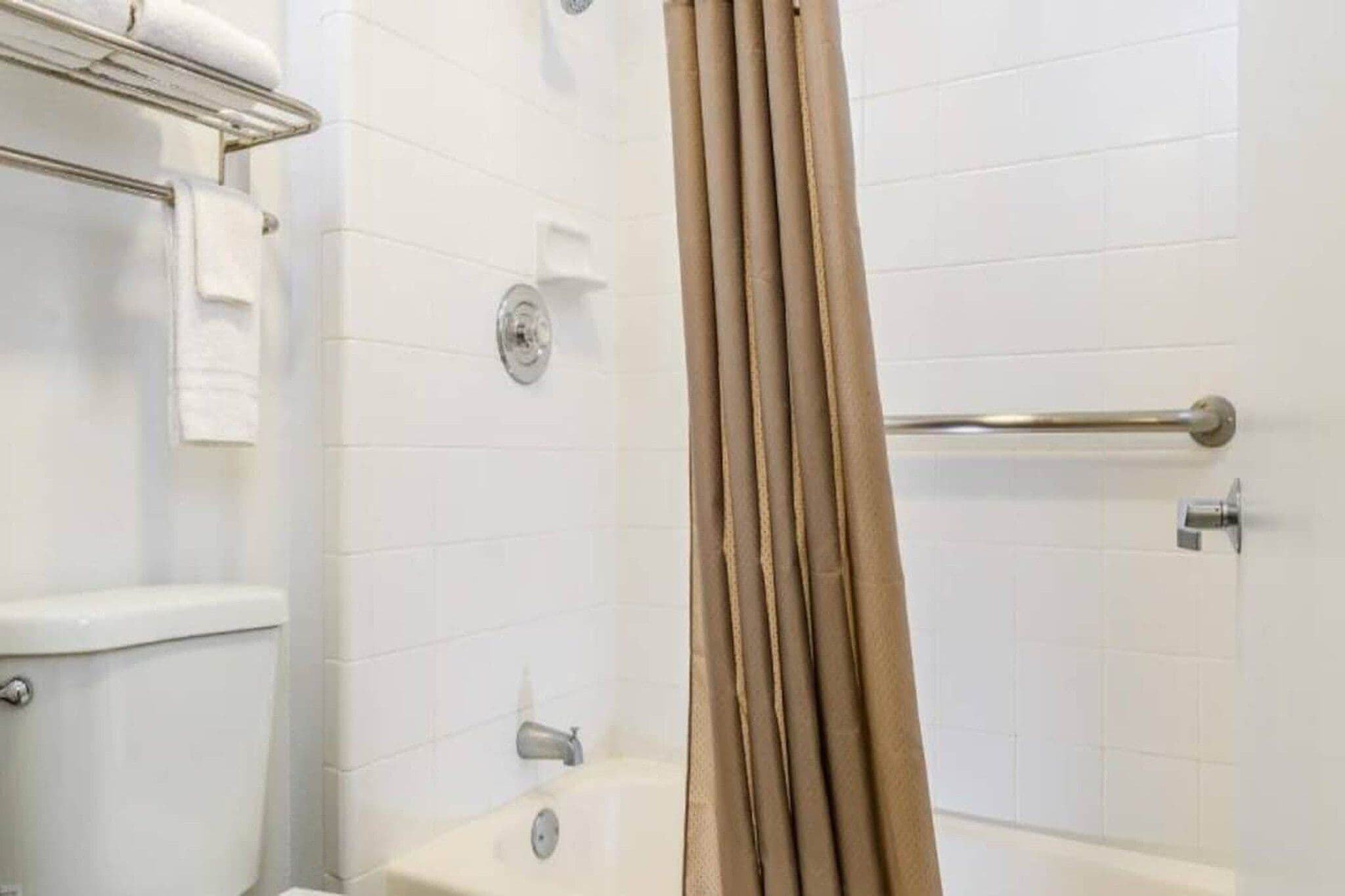 A bathroom with a bathtub, a shower curtain, and a towel rack.