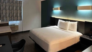 Ein Hotelzimmer mit Bett, Nachttischen, Schreibtisch und Stuhl.