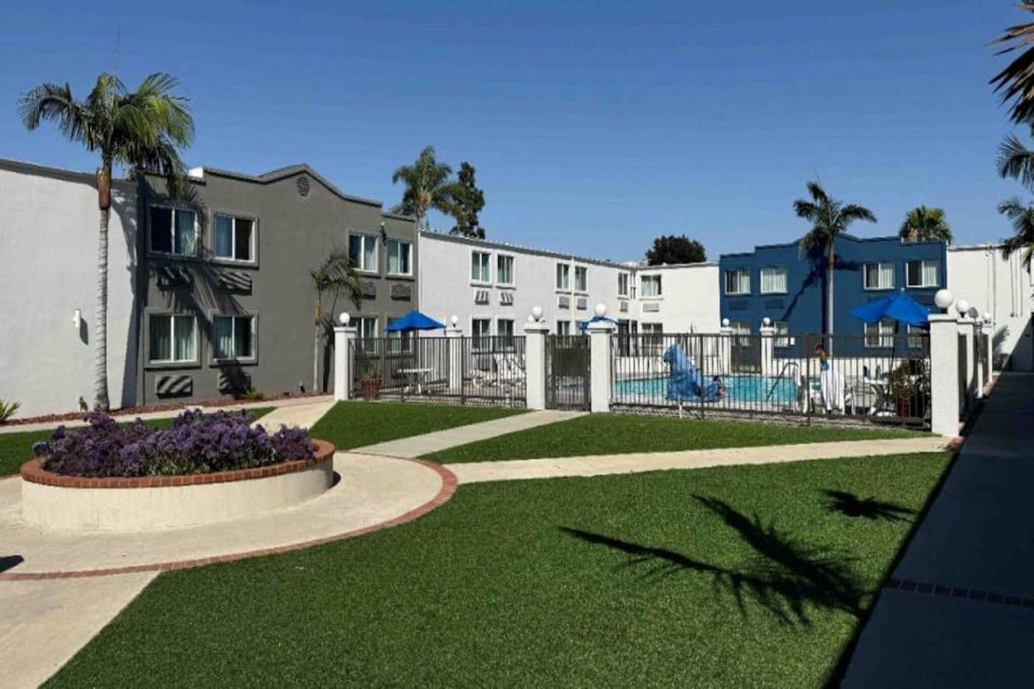 Un edificio residencial con piscina, zona vallada y césped bien cuidado.