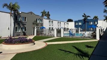Un edificio residencial con piscina, zona vallada y césped bien cuidado.