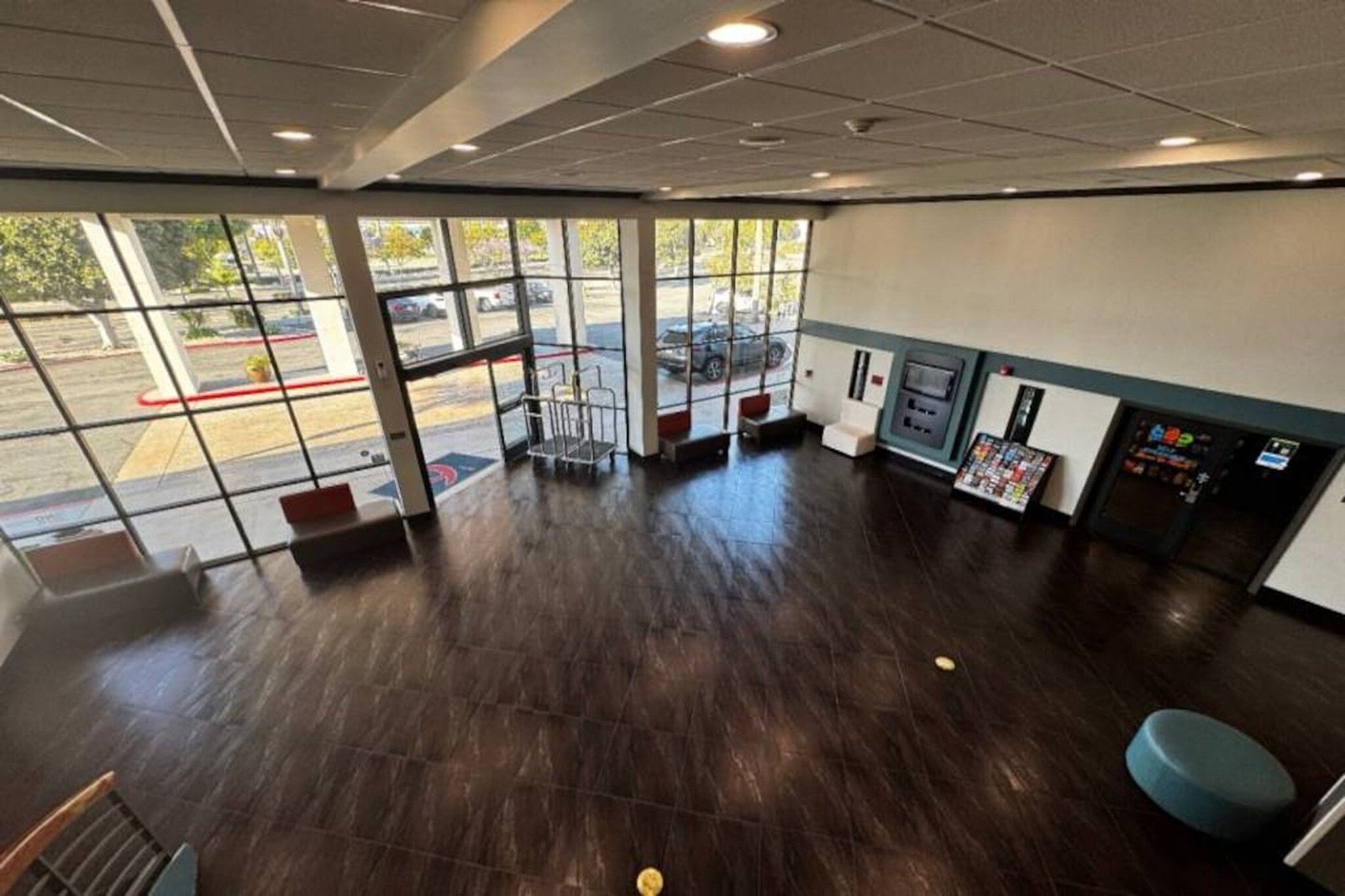 A spacious indoor area with large windows, a wooden floor, and a vending machine.