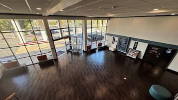 A spacious indoor area with large windows, a wooden floor, and a vending machine.