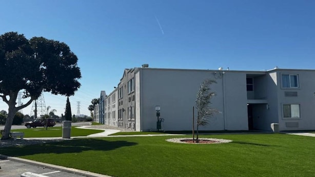 Ein modernes Gebäude mit flachem Dach, einem kleinen Baum in der Mitte und einem strahlend blauen Himmel.