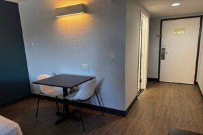 Una habitación con una mesa, dos sillas, una puerta y una lámpara en la pared.