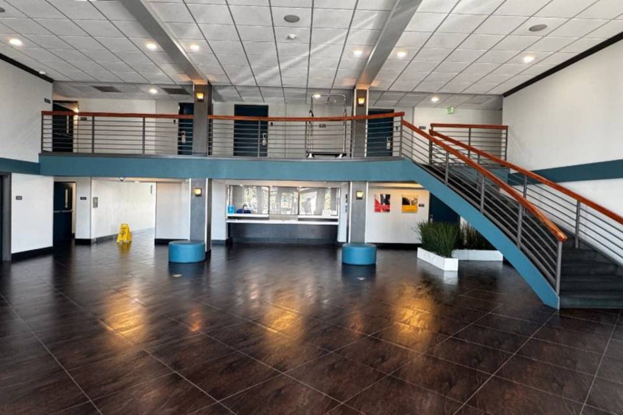 Un vestíbulo amplio con techo alto, un mostrador de recepción central y una escalera que conduce a un nivel superior.