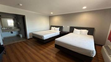 Hotellihuone, jossa on kaksi sänkyä, kylpyhuone ja pieni oleskelualue.