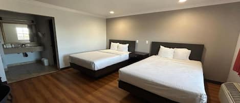 A hotel room with two beds, a bathroom, and a small sitting area.