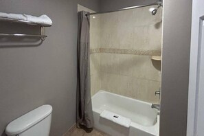 Un baño con bañera, inodoro y cortina de ducha.