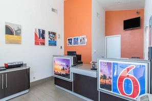 Un área de recepción con mostrador, un televisor y un cartel que indica el número 6.