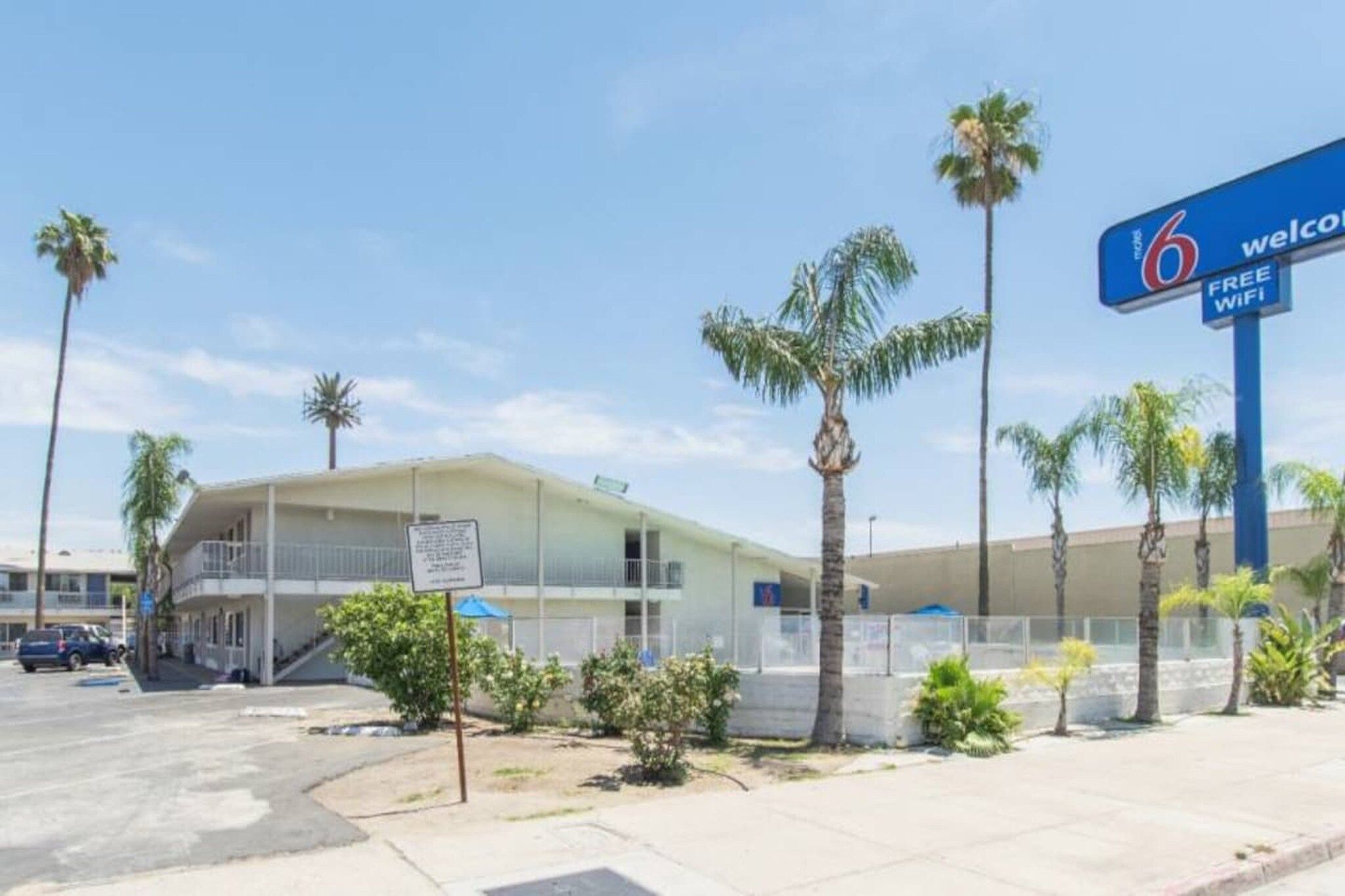 Un hotel con letrero que indica wifi gratuito, palmeras y cielo despejado.