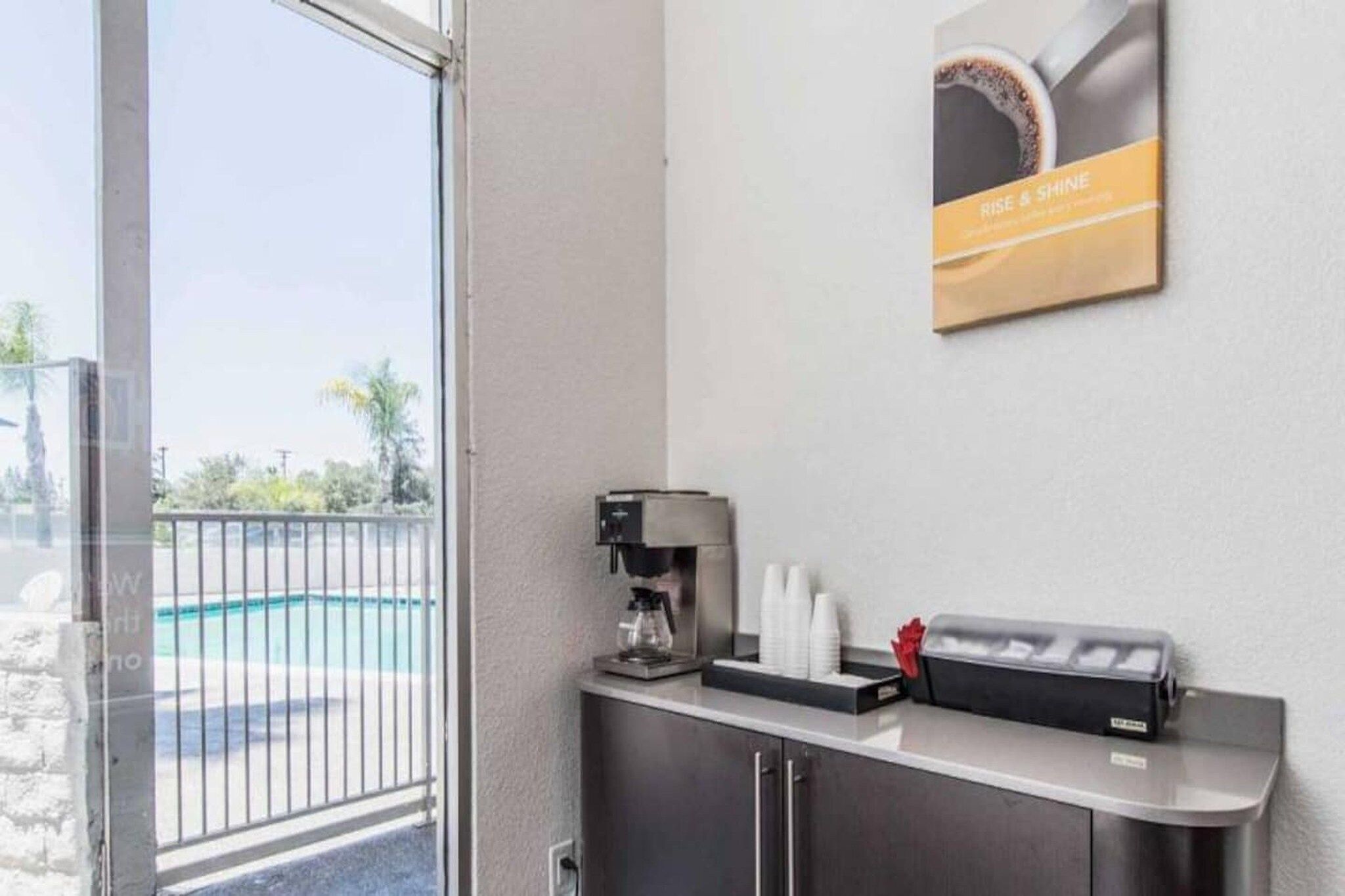 Zona de recepción con una máquina de café, tazas y un cartel en la pared.