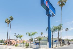 Motel con un letrero azul que indica wifi gratuito, rodeado de palmeras y un cielo despejado.