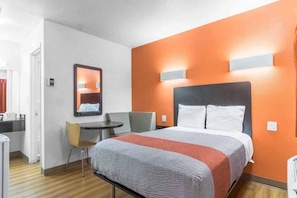 Una habitación de hotel con una cama, un escritorio, una silla y un espejo.