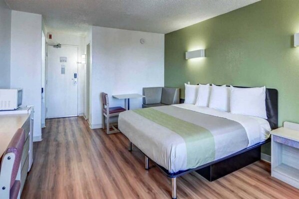 A hotel room with a bed, bedside tables, a desk, and a chair.