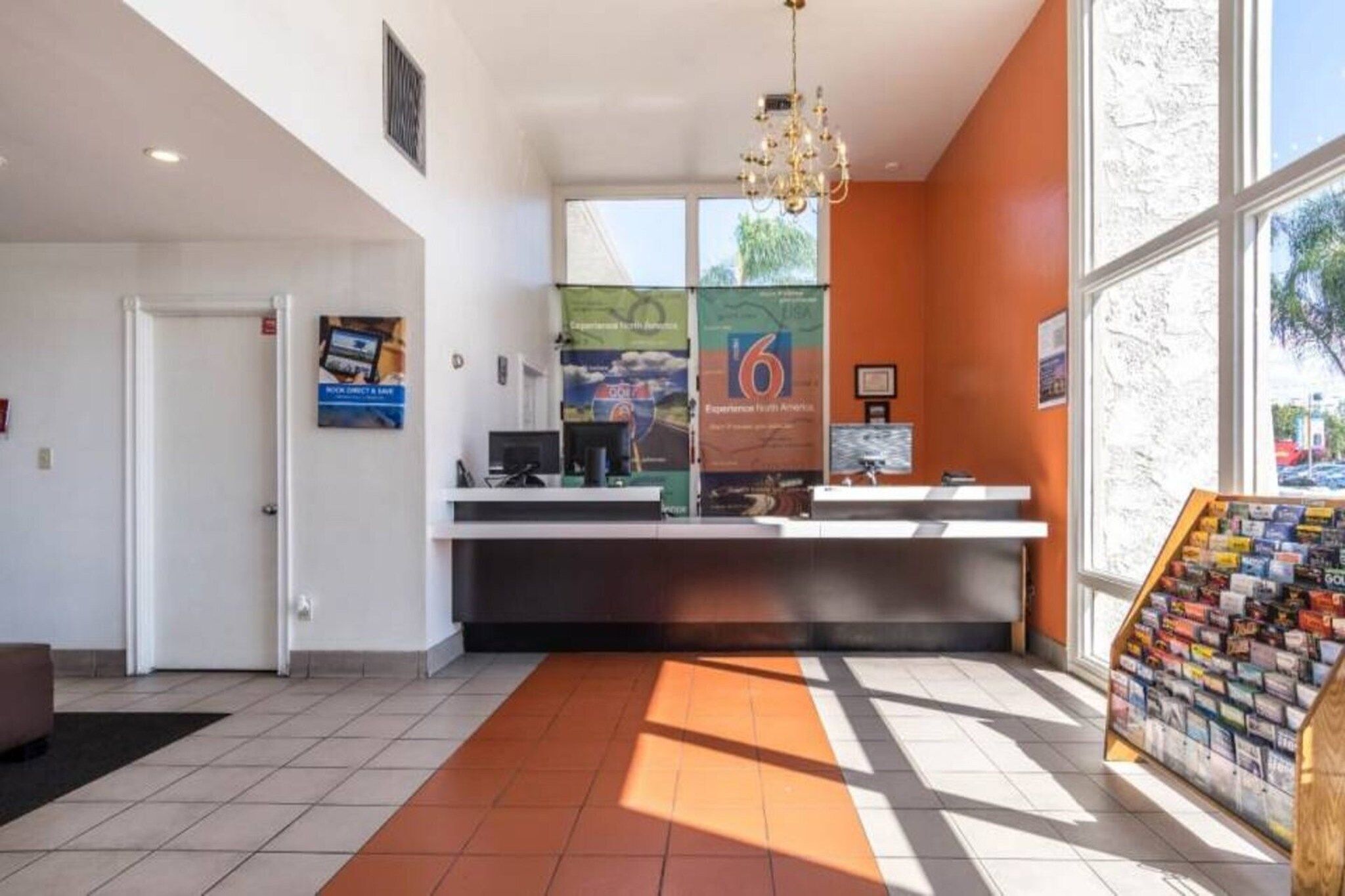 Un área de recepción con mostrador, computadora y un exhibidor de revistas.
