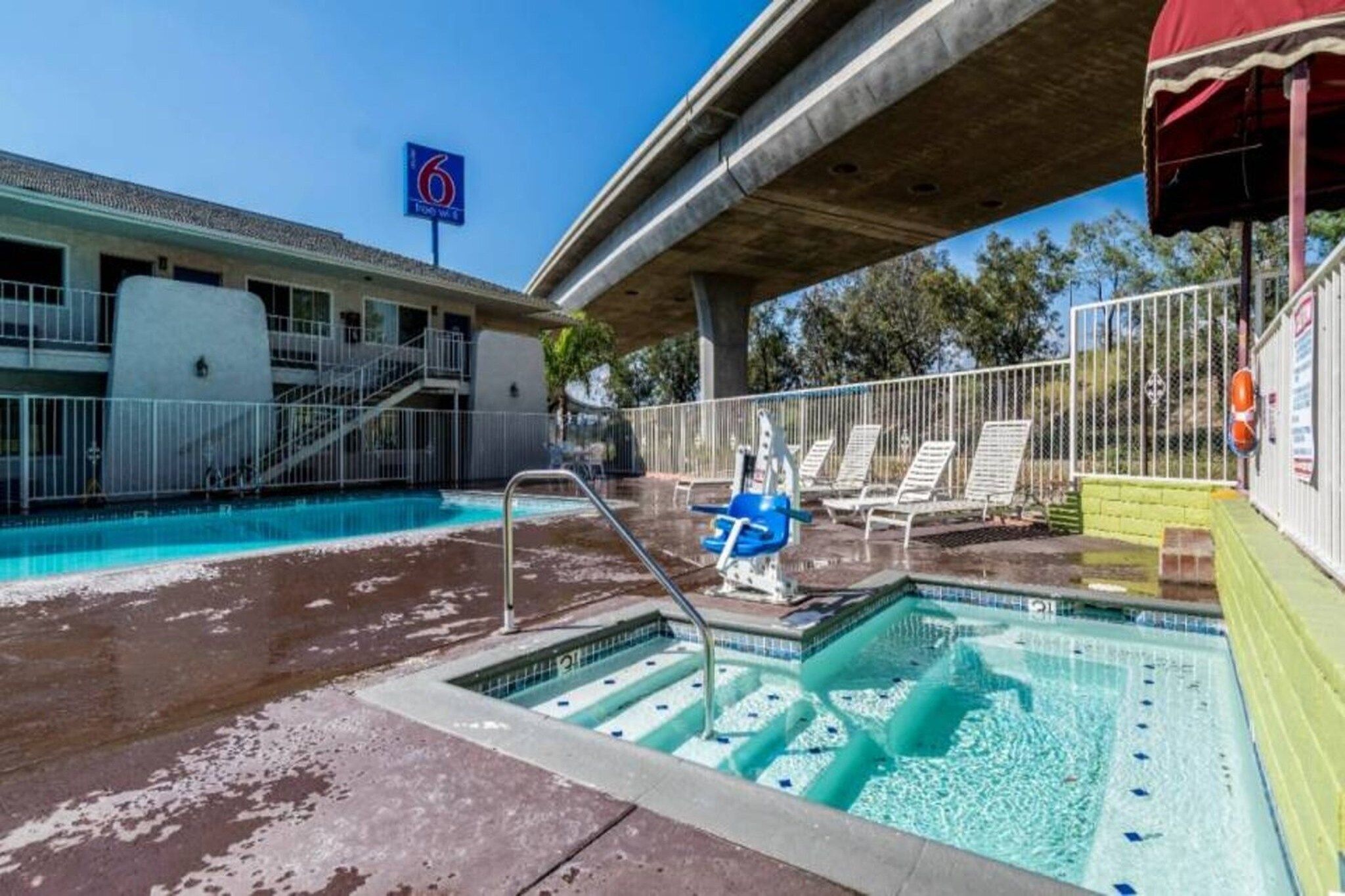 A swimming pool with a water slide, lounge chairs, and a lifeguard stand.