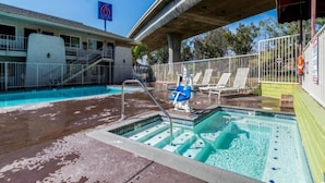A swimming pool with a water slide, lounge chairs, and a lifeguard stand. - Redlands, Ca 2 QUEEN BEDS | SMK (REDLANDS)