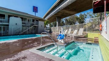 A swimming pool with a water slide, lounge chairs, and a lifeguard stand.