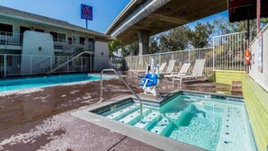 Una piscina con trampolino, sedie a sdraio e una zona coperta con tenda rossa.