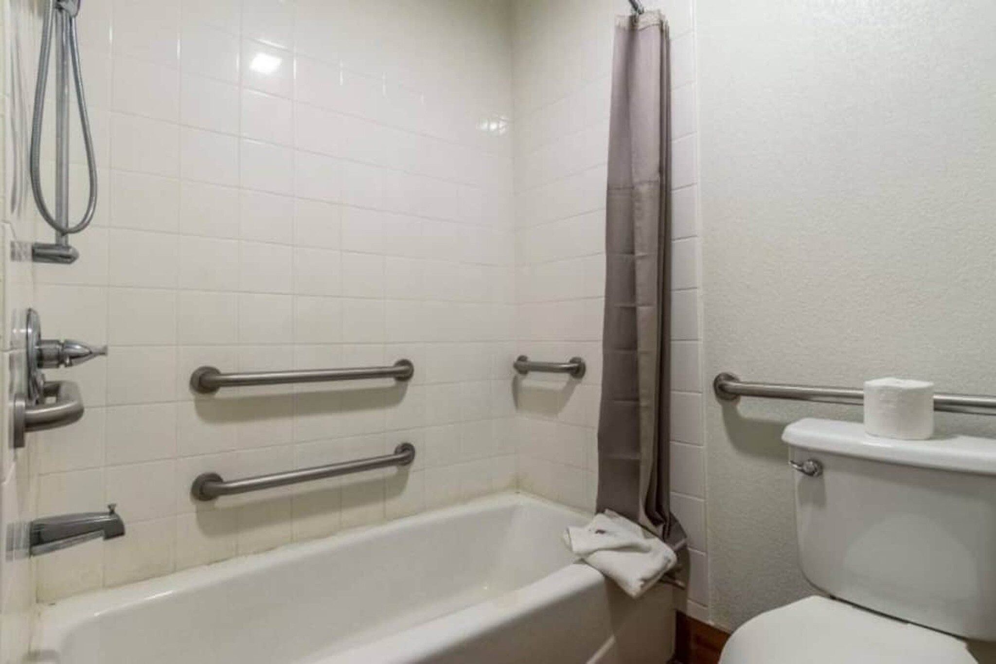 A bathroom with a bathtub, toilet, and shower area.