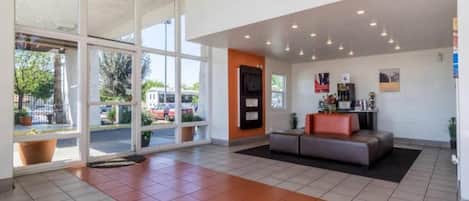A spacious lobby with a reception desk, a seating area, and large windows offering a view of the parking lot.
