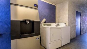 A laundry room with a dryer and washing machine, a water fountain, and a door leading to another room.