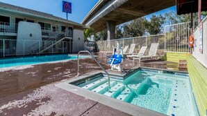 Ein Swimmingpool mit Wasserrutsche, Liegestühlen und einem Rettungsschwimmerstand.