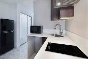A modern kitchen with a black refrigerator, a microwave, a sink, and a built-in stovetop. - 1 King - 2 Queen Beds | Non-Smoking, Kitchen (Artesia)