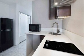 A modern kitchen with a black refrigerator, a microwave, a sink, and a built-in stovetop. - 1 King Bed | Non-Smoking, Kitchen (Artesia)